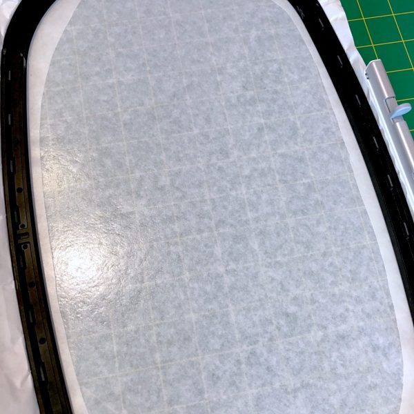 Remove the wax paper from within the score line to expose the sticky stabilizer. Using your hoop template, mark the horizontal centers of your hoop onto the sticky stabilizer.