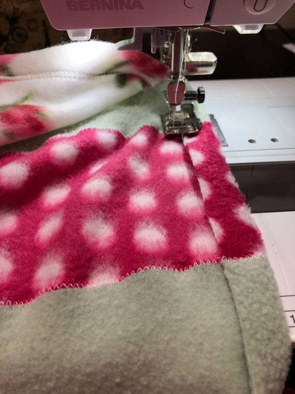 This Scrappy Fleece Blanket Tutorial is fast easy and frugal. With a few simple tools and a free evening you can make a large fleece blanket.