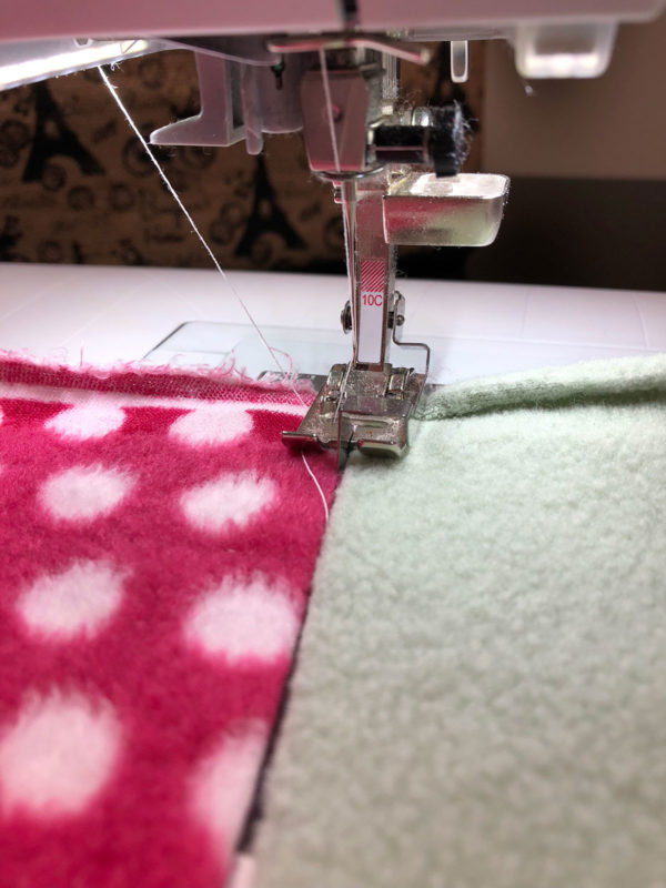This Scrappy Fleece Blanket Tutorial is fast easy and frugal. With a few simple tools and a free evening you can make a large fleece blanket.