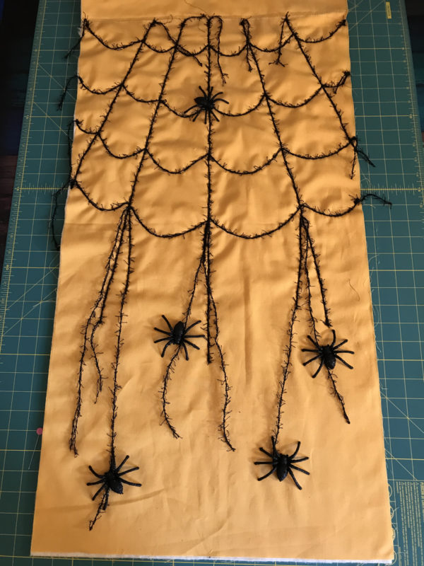 Spider Web Door Banner tutorial WeAllSew Blog - secure the spider embellishments onto the banner by simply tying the spiders onto the dangling yarns