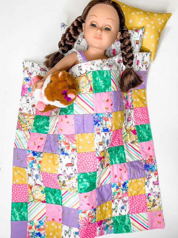 18 inch doll sleeping with patchwork quilt covering her