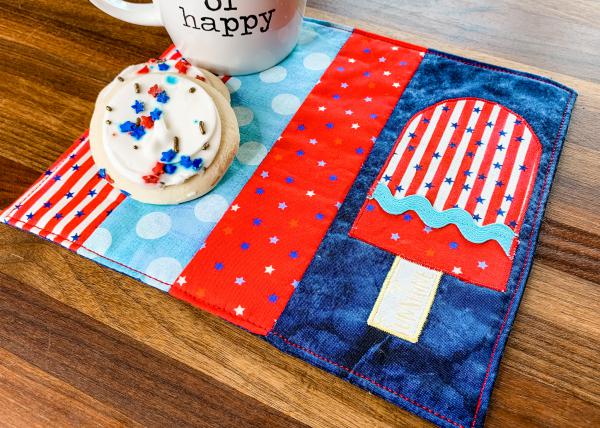 "Patriotic Mug Rug with Appliqué Popsicle” is a Free Patriotic Quilted Coaster or Mug Rug Pattern designed by Sharon Madson from We All Sew!
