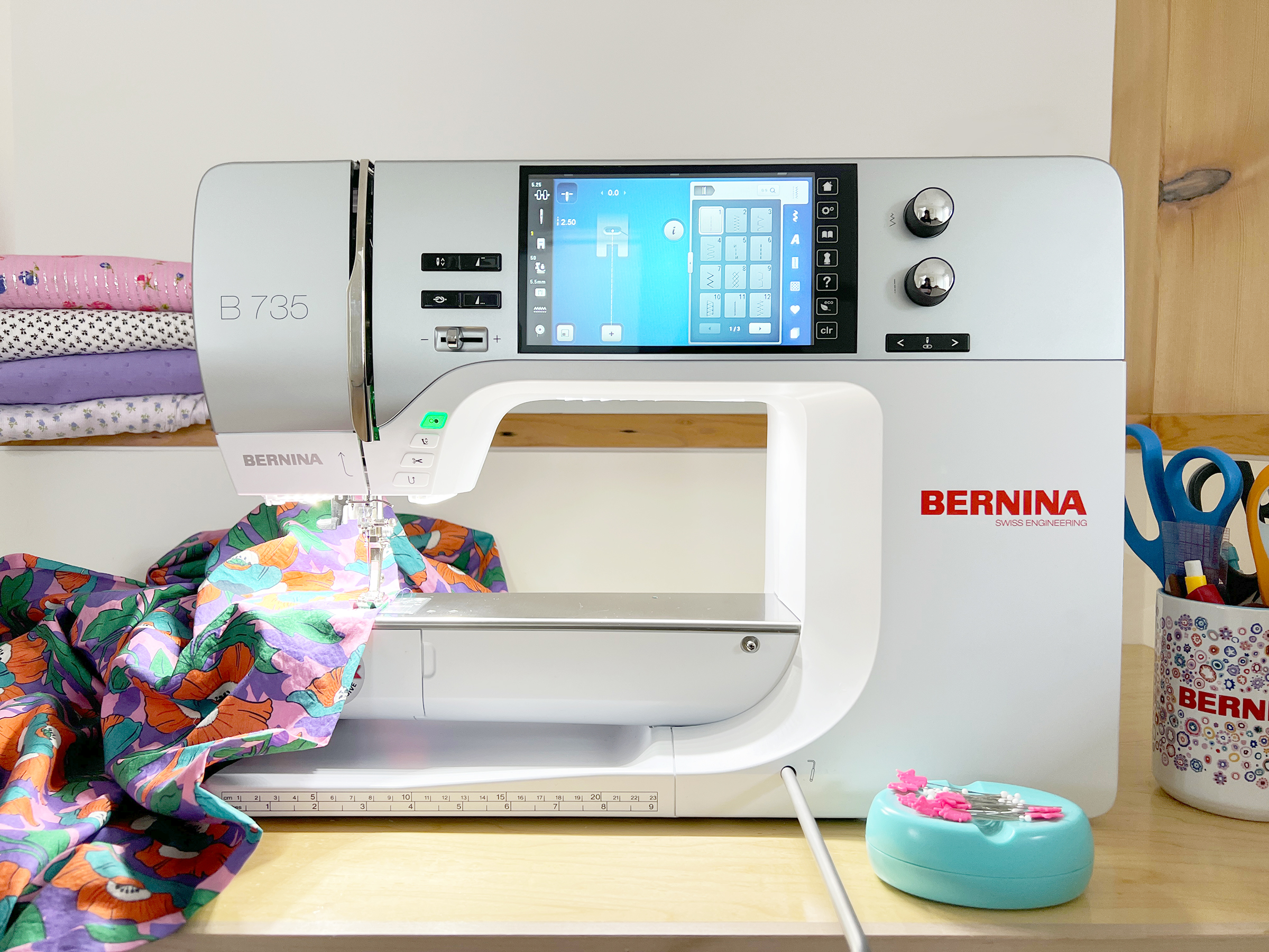 Close up shot of a BERNINA B735 sewing machine with colorful floral fabric under the needle.