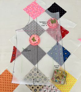 A sewing pattern tissue for a jacket front is laid on top of patchwork fabric.