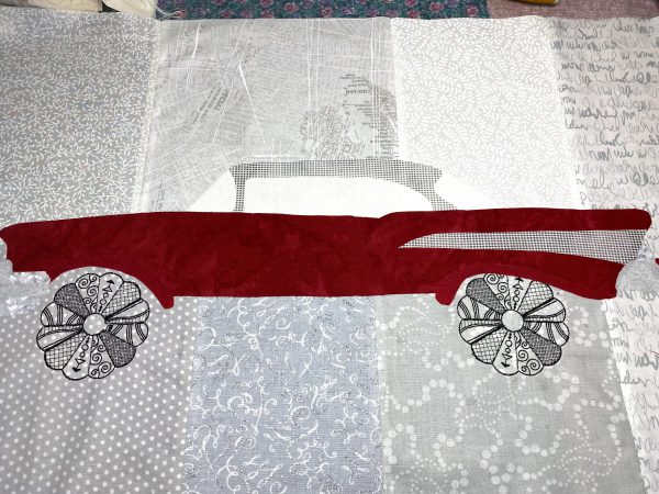 Aligning the car with embroidered wheels and blending onto the prepared background fabric. 
