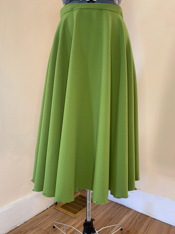 A green skirt on a mannequin with an evenly trimmed hem.