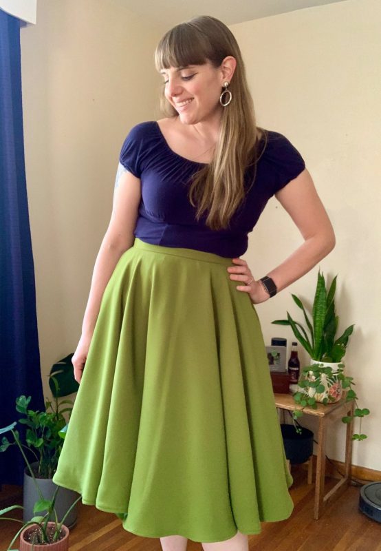 A white woman wearing a green skirt and a blue top.