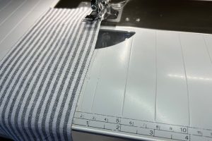 Modern_Farmhouse_Kitchen_Towels_22_fabric_strip_along_mark_on_slide_on_table_BERNINA_WeAllSew_Blog_1200x800px