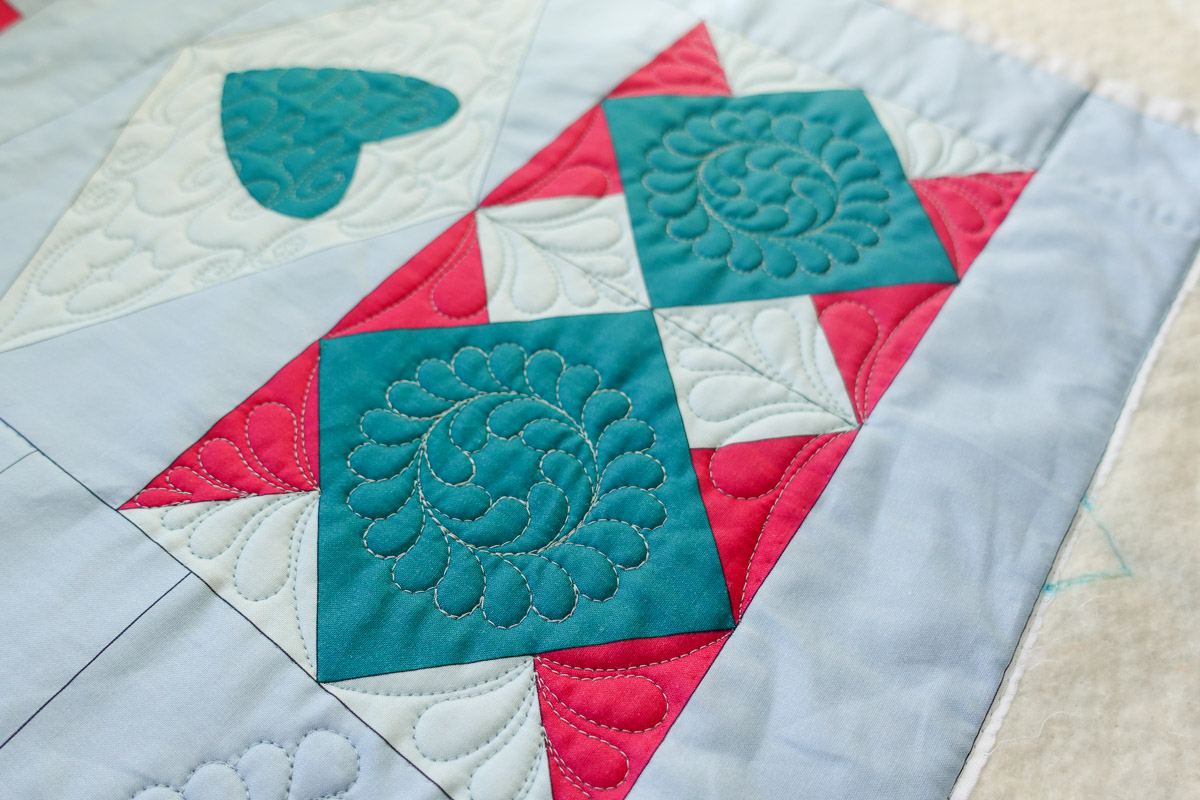 a quilted motif on the blue diamond block of the Jump for Joy quilt.