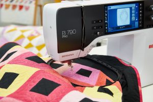 quilting through a hoop onto a red, orange, and yellow quilt using the B 790 PRO