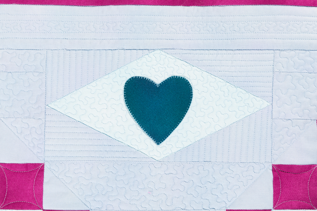 blue heart on a white quilted background.