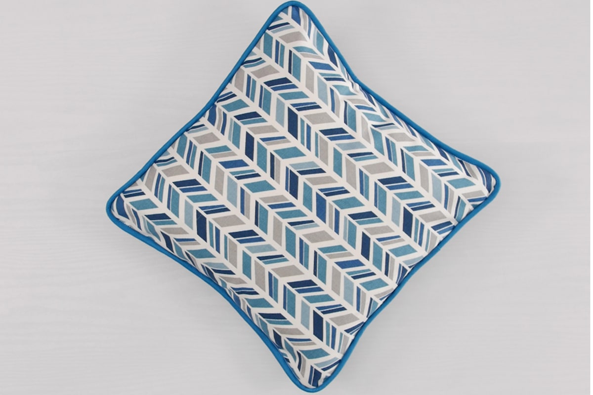 a blue, white, and yellow chevron-patterned pillow on a light background