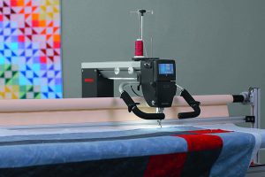 Longarm machine quilting a blue fabric top.