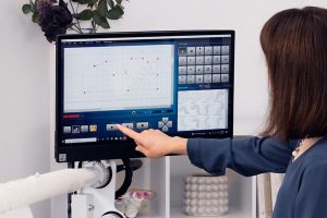 a woman pressing Play on the display screen of the BERNINA Q-matic.