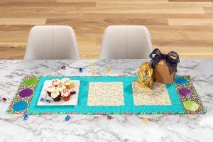 overhead view of a teal and floral cupcake table runner on a marble table