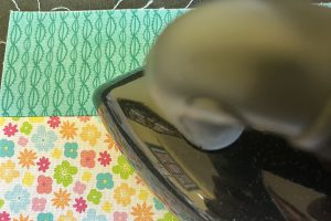 overhead view of an iron pressing seams on floral and teal fabric.