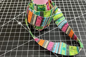 multi-colored binding wrapped around a pink thread spool.