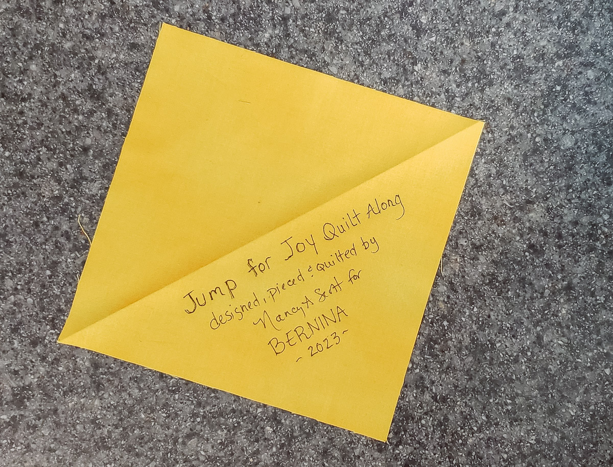 A yellow square of fabric, with blank handwriting on one half of it.