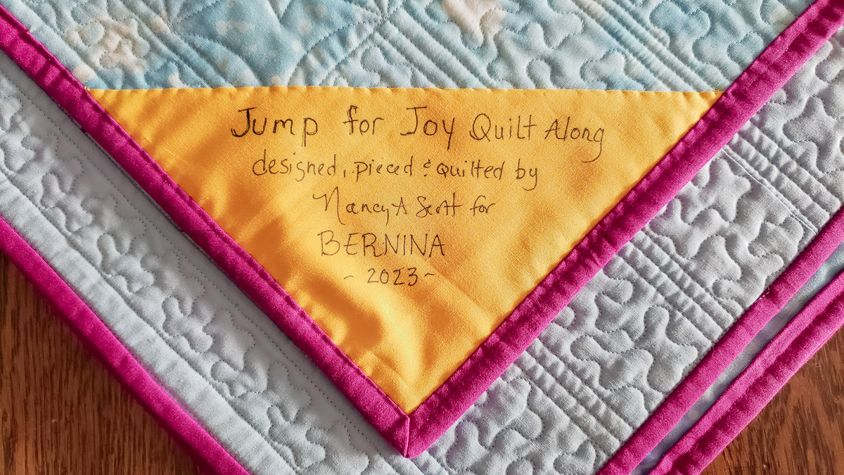 A close up of a yellow quilt label sewn into the binding of a quilt.