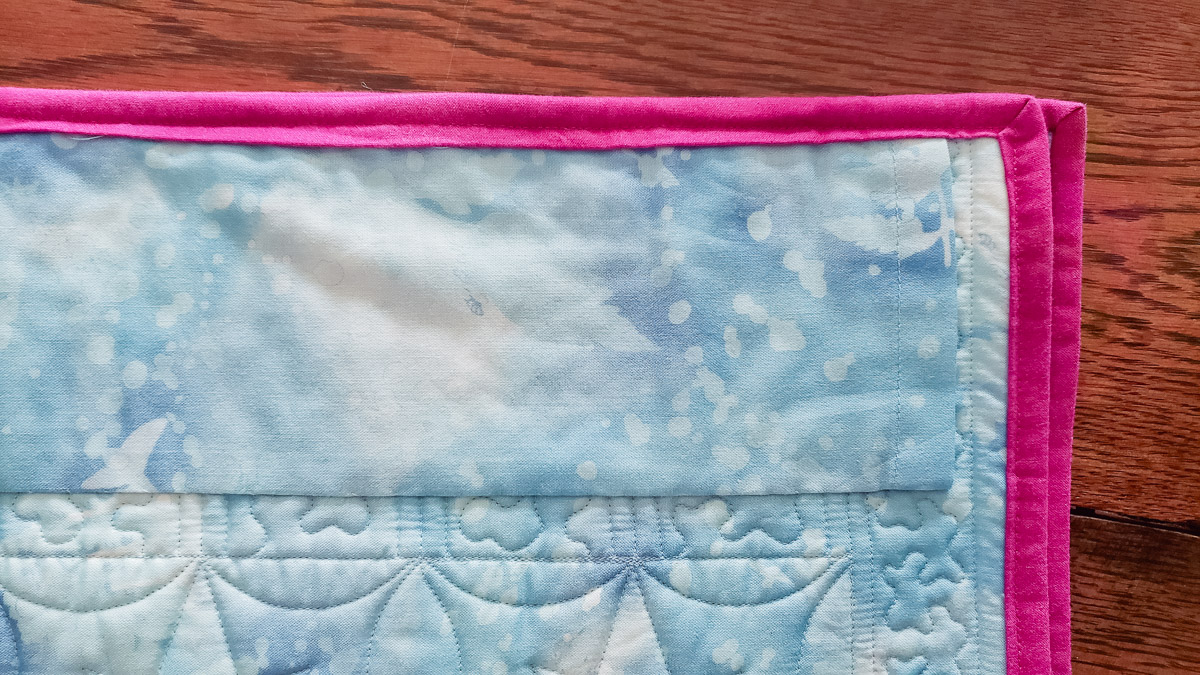 a close up view of a hanging sleeve sewn into the quilt binding.