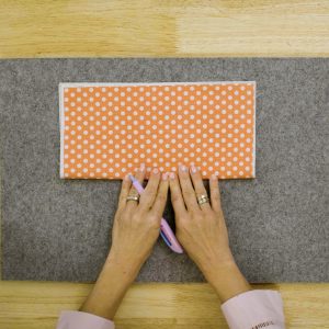 orange polka dot fabric being folded in half lengthwise