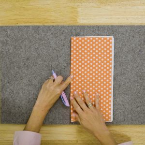 orange polka dot fabric being folded in half widthwise