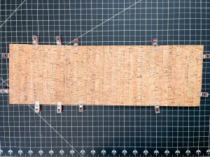 Cork pinned with clips and laying on a black grid background