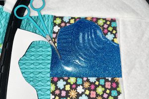 scissors used to trim away excess vinyl around finished embroidery motif