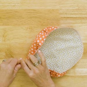 a hand is pulling two cords to cinch and gather a fabric circle