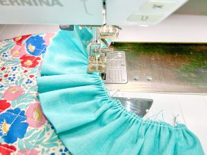 Close up view of blue ruffle being sewn to bib