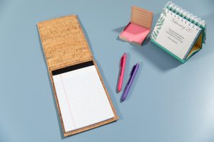 An open notebook with pens and office supplies arranged around it.