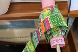 multi-color fabric binding on a pink spool