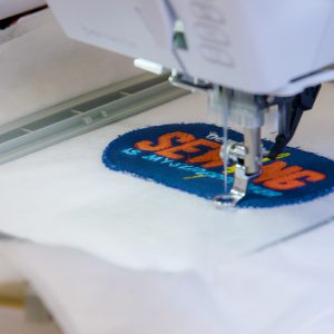 close-up view of the embroidery foot stitching a satin border stitch around the patch