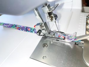 Side view of binding fabric being fed through the sewing machine foot.