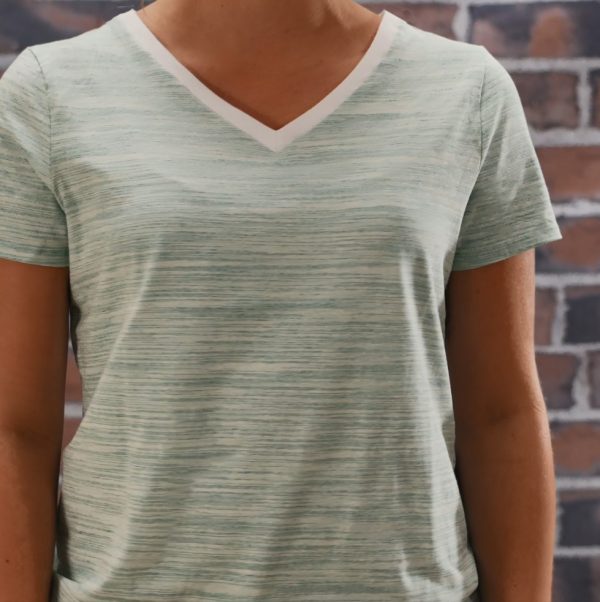 Woman wearing green V-neck shirt against brick background