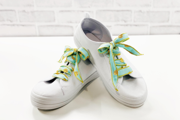 White shoes with mint green and orange laces on white background