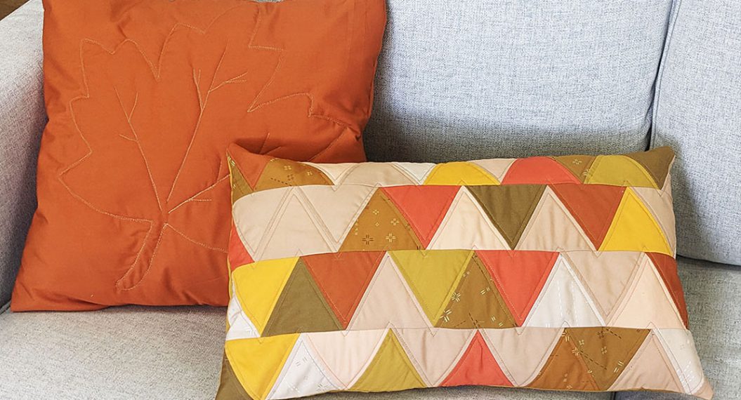 Two Fall-theme colored pillows on gray couch