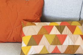 Two Fall-theme colored pillows on gray couch