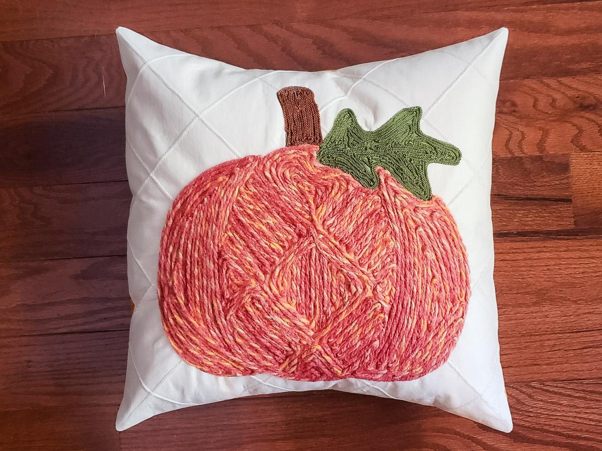 Decorative Pumpkin Pillow in orange and white on a wood background