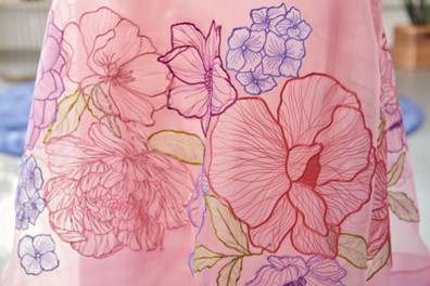 close up view of embroidered flowers on pink organza