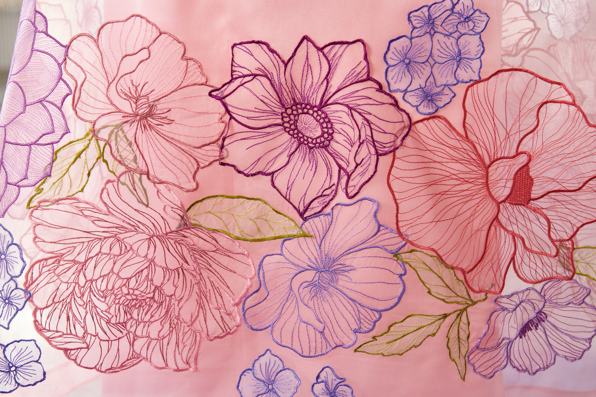 closeup view of embroidered flowers on pink organza