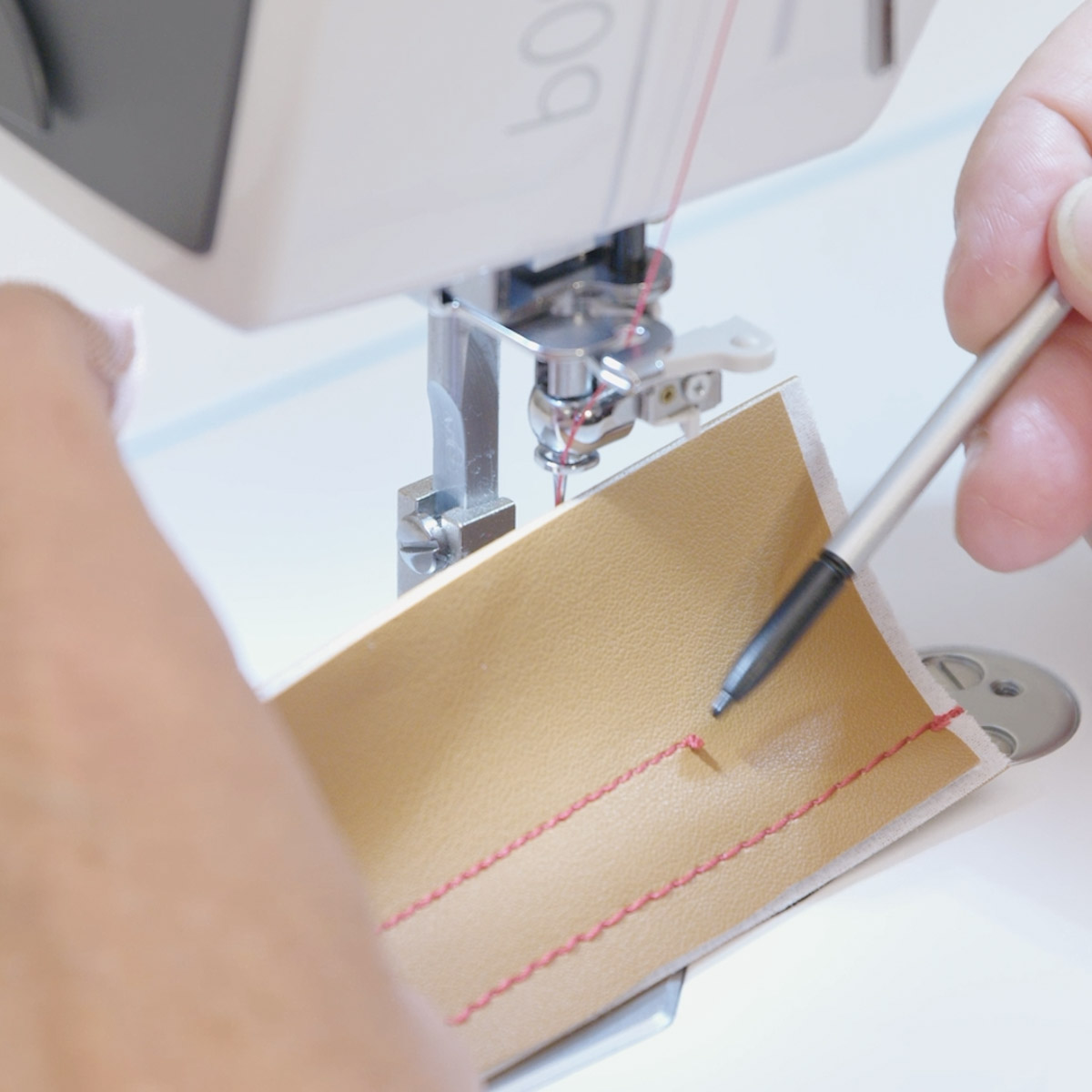 A close up view of the secured end of red thread on brown leather