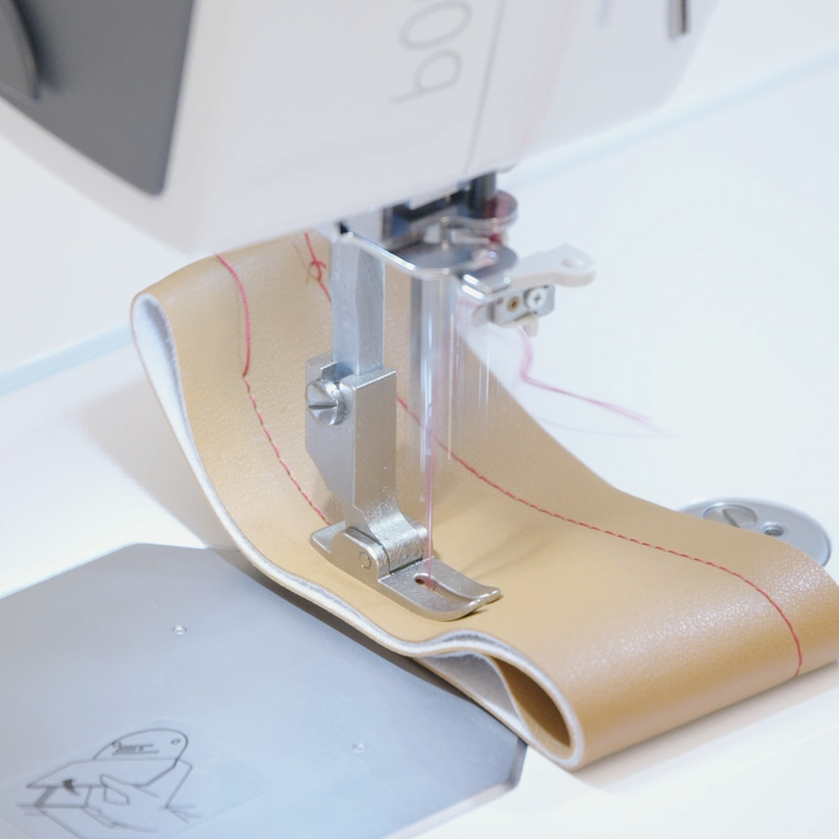 Sample leather fabric being sewn with red thread