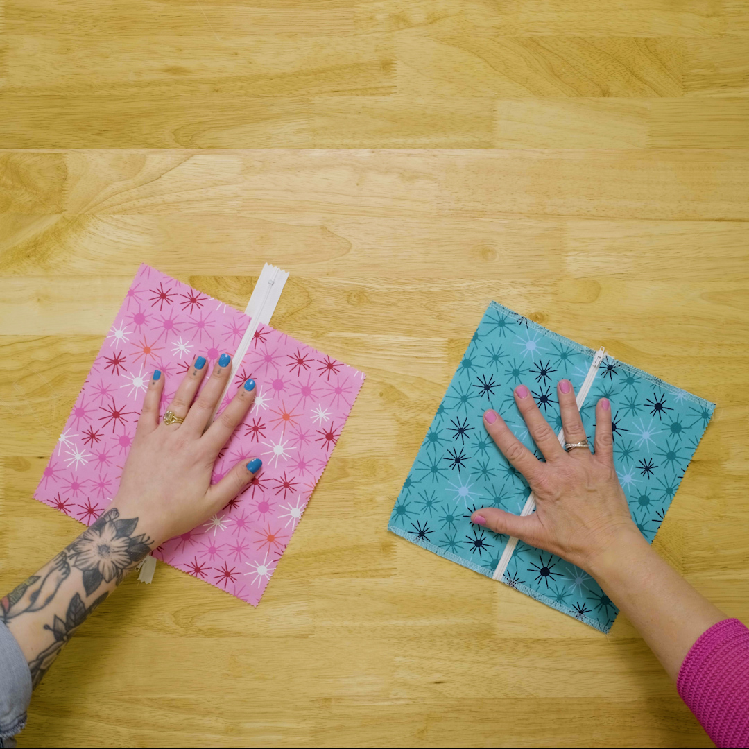 overhead view of zippered fabric samples with hands on top