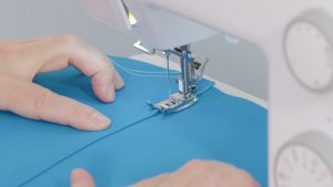 Overhead view of blue fabric being topstitched