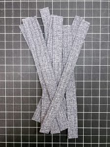 Arrangement of grey fabric strips on a black cutting board
