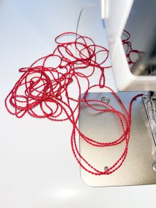 small pile of red threat on a sewing machine