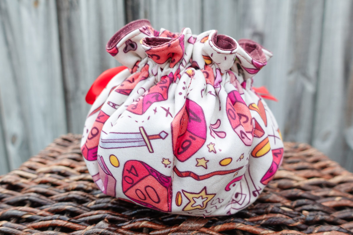 A colorful handsewn DND Dice Bag placed on a brown wicker surface
