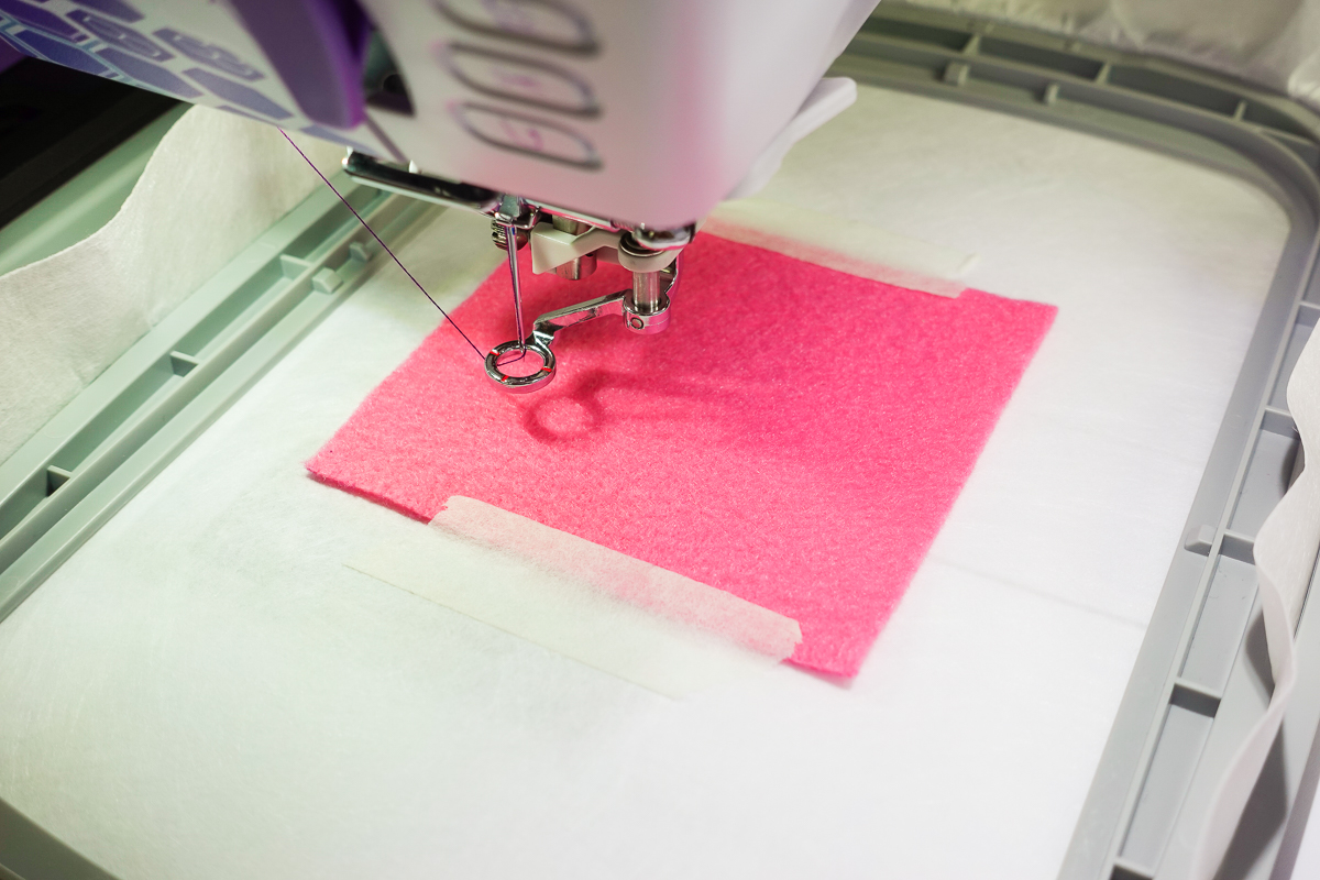 overhead view of the embroidery foot on the b79 preparing to stitch on pink felt