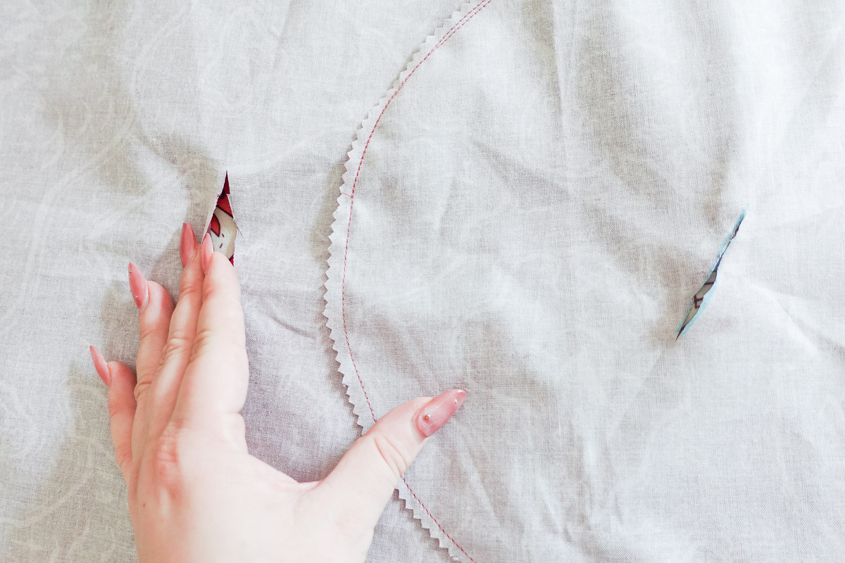 a hand touching pieces of fabric with slits cut into the lining